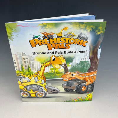 Paperback book  of the prehistoric pals Brontie and pals build a park. The construction dinosaurs love to dig and build for a better world. Brontie is a Brontosaurus excavator, Gronk is a stegosaurus-skid Loader  and Bianca is a iguanodon land mover.