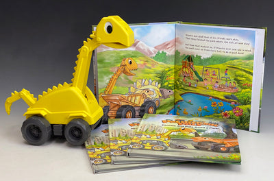 This is side view of Brontie the dinosaur construction excavator rolling up on a stack of three Prehistoric Pals hardcover children's Books. The books are for ages 3 and up!